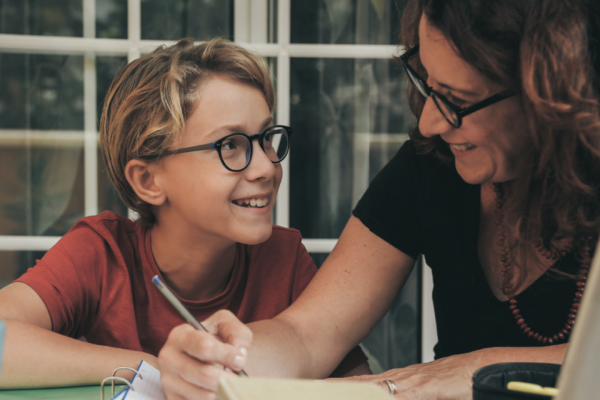 Mother smiling at son while home schooling him.